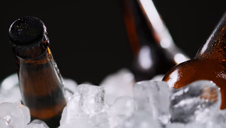 Nahaufnahme-Von-Glasflaschen-Mit-Kaltem-Bier-Oder-Alkoholfreien-Getränken,-Die-In-Einem-Mit-Eis-Gefüllten-Eimer-Vor-Schwarzem-Hintergrund-Kühlen-2